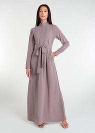 This Box Pleat Abaya Taupe features a fluid, A-line cut with a neat box pleat that runs from the high neck line to the bottom of the garment. The abaya is lightweight and airy, and a slip is necessary to wear underneath. 