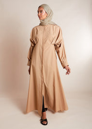This Maxi Shirt Dress Sand features cuffed sleeves and pockets, giving the appearance of a tucked-in shirt and skirt when it is actually a one-piece outfit. Pleats at the waist create a cinch, while the top half remains loose for a comfortable fit. The dress is cut in an A-line style. Neutral beige tone.