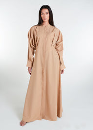 This Maxi Shirt Dress Sand features cuffed sleeves and pockets, giving the appearance of a tucked-in shirt and skirt when it is actually a one-piece outfit. Pleats at the waist create a cinch, while the top half remains loose for a comfortable fit. The dress is cut in an A-line style. Neutral beige tone.