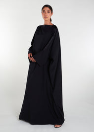 This loose fit classic black kaftan features a luxurious satin strip across the neck line and sleeves, adding an elegant touch to its modest cut silhouette. Ideal for various occasions.