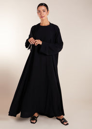 This elegant Two Piece Open Abaya set includes a Full Sleeve matching inner dress. Perfect for everyday wear, it can also be dressed up with accessories for an evening look. The open abaya can be worn as a maxi on its own or paired with the inner dress for a stylish ensemble. In black.
