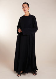 This elegant Two Piece Open Abaya set includes a Full Sleeve matching inner dress. Perfect for everyday wear, it can also be dressed up with accessories for an evening look. The open abaya can be worn as a maxi on its own or paired with the inner dress for a stylish ensemble. In black.